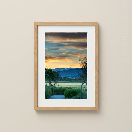 Framed artwork of a landscape with a sunset over mountains on a beige wall.