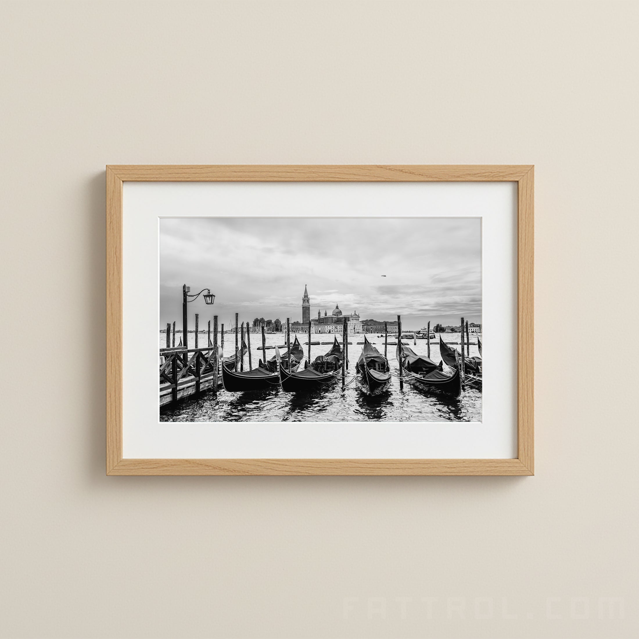 Framed black and white photograph of gondolas on a canal with a cityscape in the background.