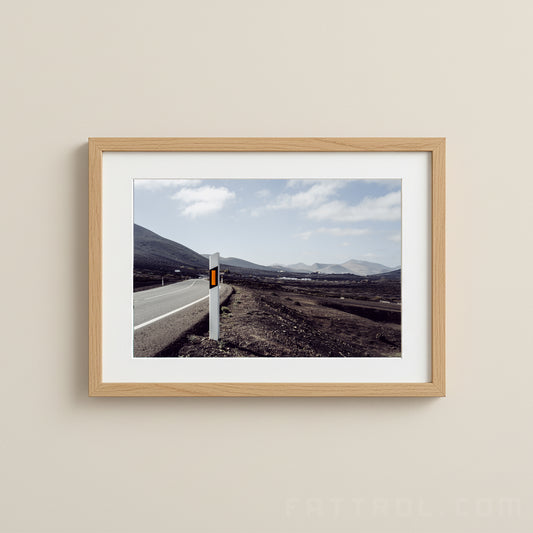 Winding volcanic road in Lanzarote under a soft blue sky.