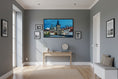 Load image into Gallery viewer, Modern living room with a television mounted on a gray wall, a desk, and decorative items.
