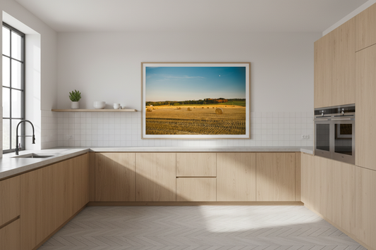 Golden harvest field with round hay bales under a clear blue sky at sunset
