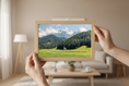 Load image into Gallery viewer, Person holding a wooden-framed picture of a mountain landscape in a living room.

