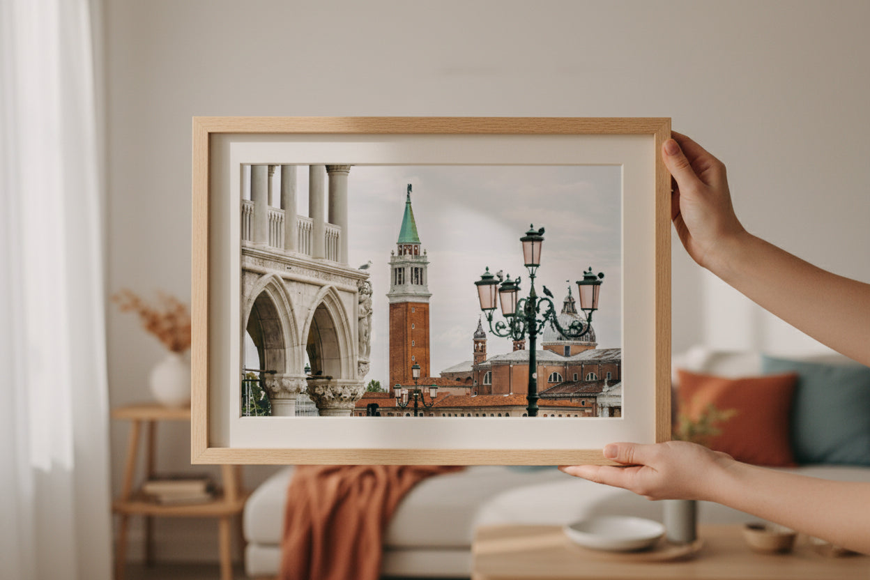 Person holding a framed photograph of a cityscape with a clock tower and street lamp.