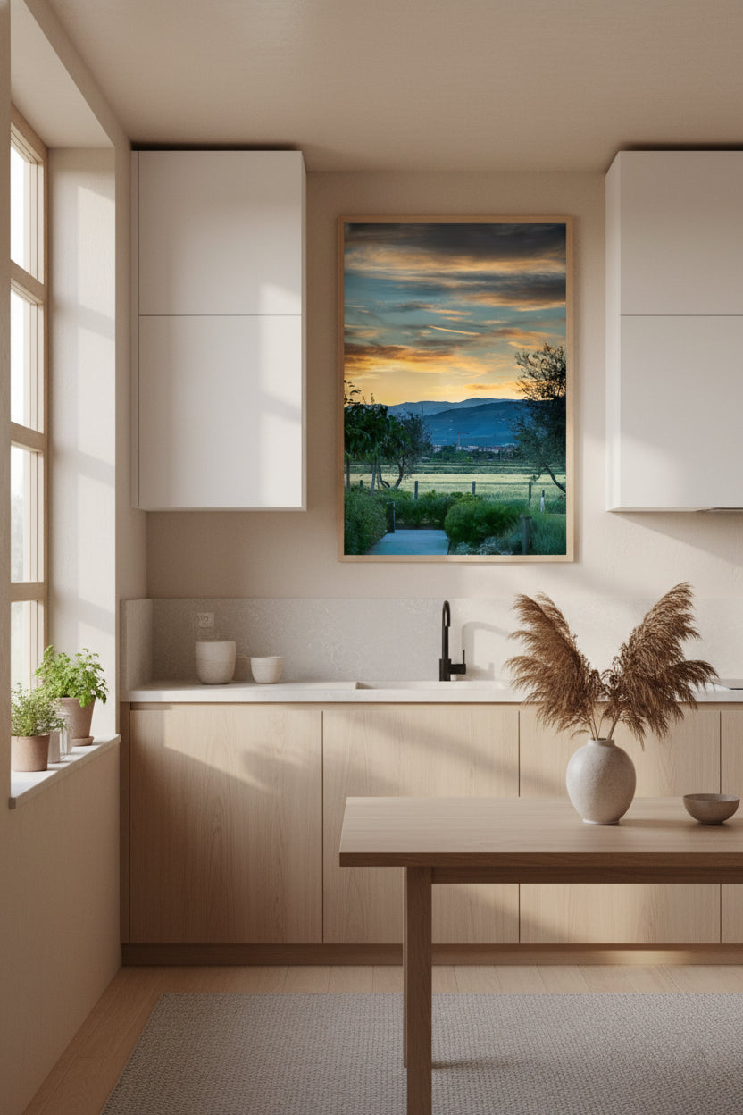 Modern kitchen with a painting of a sunset over a field on the wall.