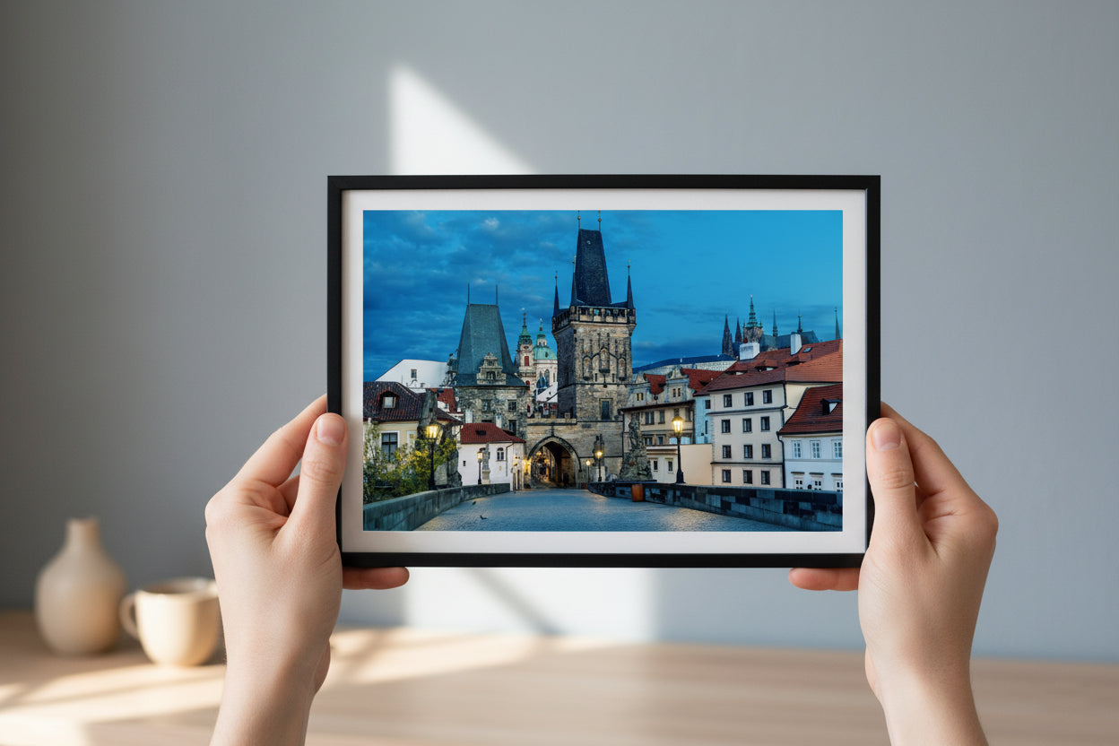 Framed picture of a cityscape held by hands against a plain wall.