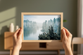 Load image into Gallery viewer, Frosty morning nature poster with sunlight filtering through tall trees beside a calm winter river.

