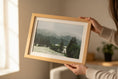 Bild in Galerie-Betrachter laden, Person holding a framed picture of a forest landscape indoors.
