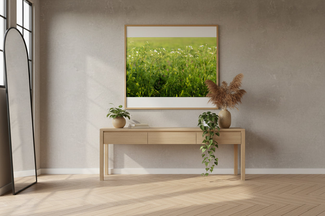 Modern interior with a wooden console table, decorative plants, and a framed picture of a green field.