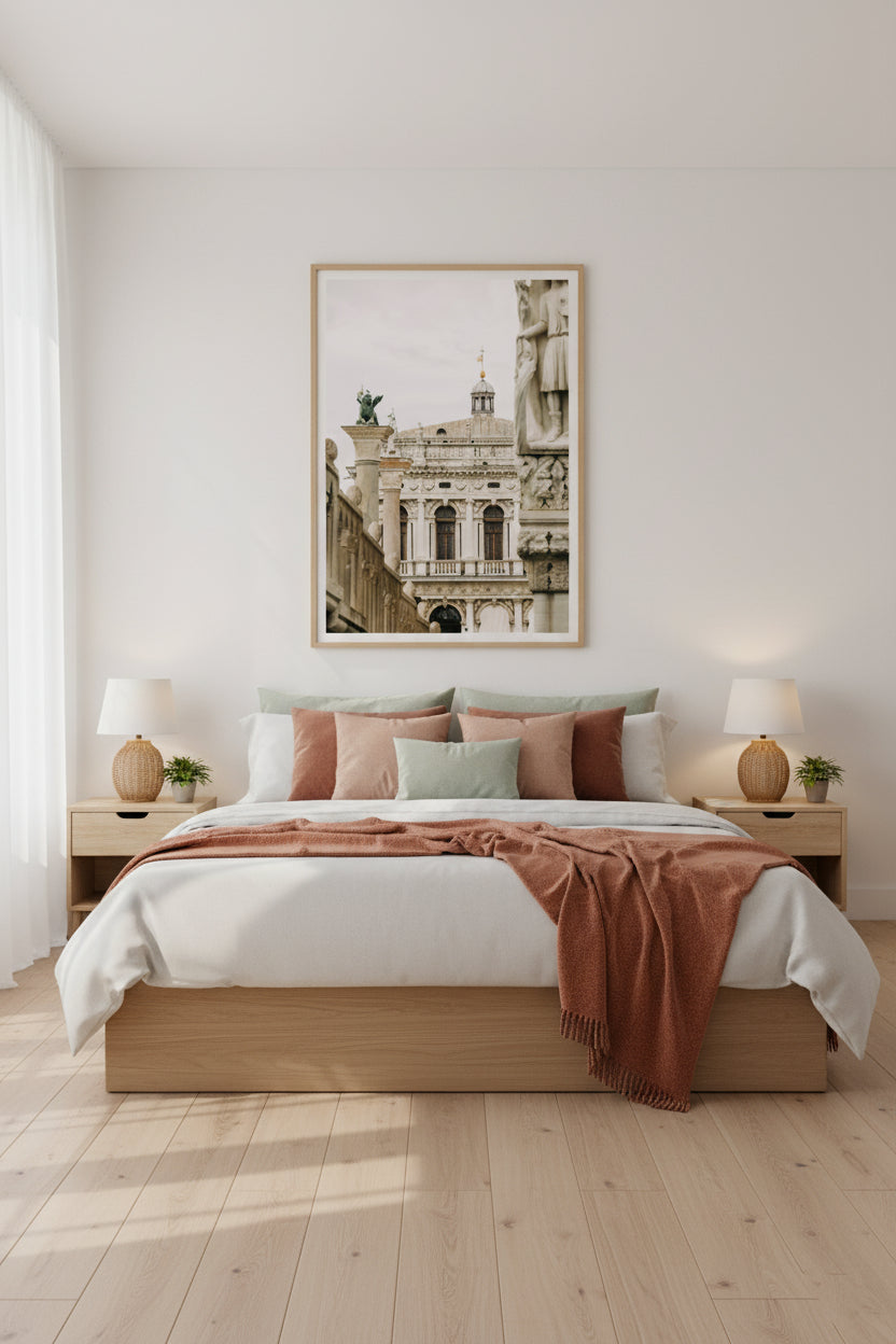 Neatly made bed with pink and white bedding in a bedroom with a framed picture on the wall.