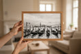 Load image into Gallery viewer, Person holding a framed black and white photograph of a waterfront scene with gondolas.

