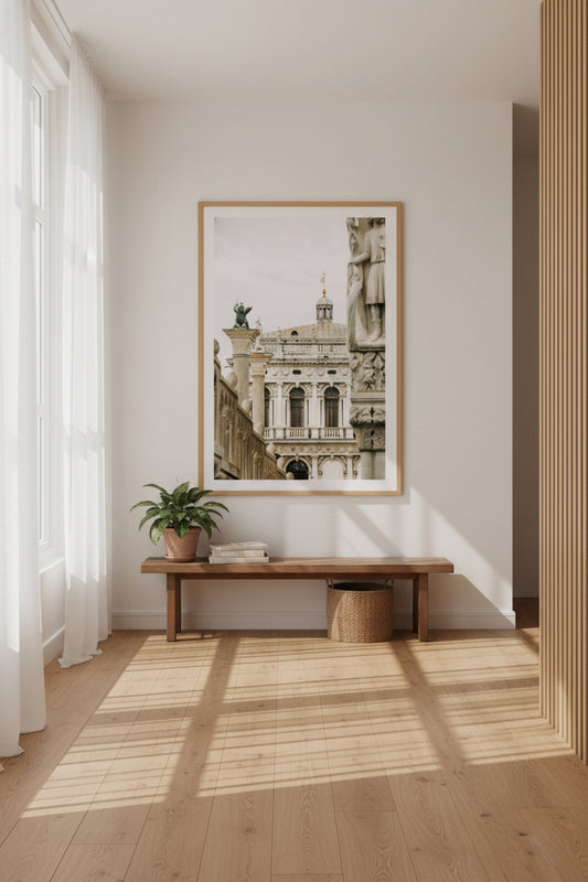 Framed artwork on a wall above a wooden bench in a well-lit room.