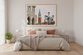 Load image into Gallery viewer, Bedroom with a large framed photograph of a cityscape on the wall above the bed.
