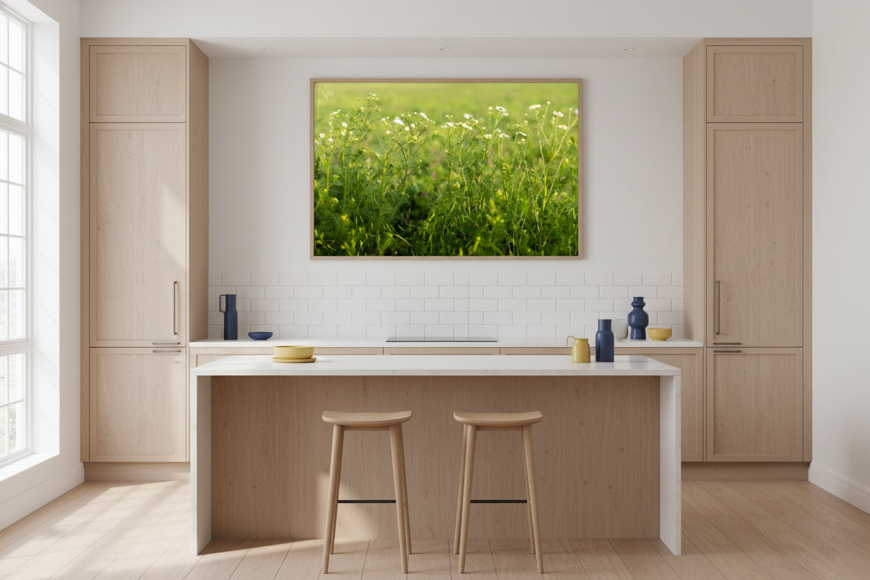 Modern kitchen with wooden cabinets, a white island, and a painting of a green field.